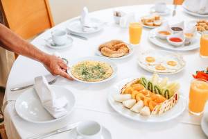 Reichhaltiges Frühstücksbuffet im Hotel mit Eiern, Bagels, Obst und Orangensaft.