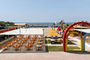 Strandterrasse des Megasaray Resort Side mit Tischen, Stühlen und Sonnenschirmen.