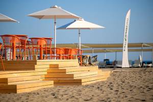 Strandterrasse im Megasaray Resort Side mit orangefarbenen Stühlen und Sonnenschirmen.