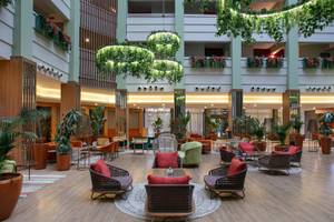 Lobby des Megasaray Resort Side mit runden Tischen, Stühlen und Pflanzen.