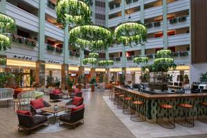 Lobby des Megasaray Resort Side mit Sitzgelegenheiten, Bar und begrünten Deckenleuchten.