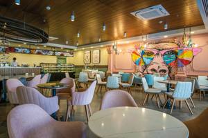 Innenbereich des Restaurants im Seaden Quality Resort & Spa mit bunten Wänden und runden Tischen.