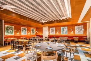 Innenbereich des Restaurants im Rixos Gulf Hotel Doha mit runden Tischen und Stühlen.