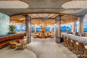 Innenansicht der Lounge im Rixos Gulf Hotel Doha mit Holzmöbeln und Panoramafenstern.
