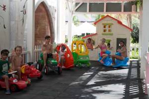 Kinder auf Spielzeugautos im Spielplatzbereich des Royal Taj Mahal Hotels