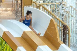Ein kleines Mädchen rutscht auf einer Wasserrutsche im Waldorf Astoria Doha Lusail.