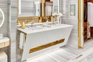 Luxuriöses Badezimmer im Fairmont Doha Hotel mit Marmorwänden, Doppelwaschbecken und Spiegeln.