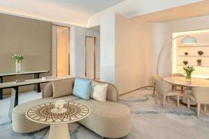 Wohnbereich im Fairmont Doha Hotel mit Couch, Tisch, Stühlen und Dekor.