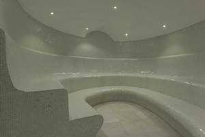 Innenansicht der Sauna im Royal Taj Mahal Hotel mit weißen Fliesen und gebogenen Bänken.