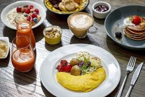 Frühstücksbuffet im Hyatt Regency Oryx Doha mit verschiedenen Gerichten und Getränken auf einem Holztisch.