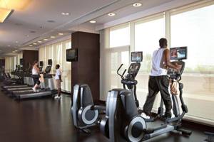 Fitnesscenter im Hyatt Regency Oryx Doha mit Läufern auf Geräten und Fernsehern