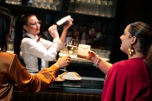 Vier Frauen an einer Bar im Four Seasons Hotel Doha, eine bedient die Gäste, während die anderen einen Drink genießen.