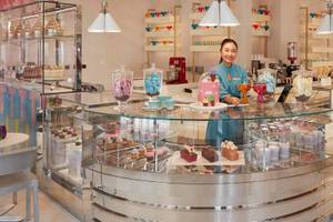Eine Verkäuferin im Mandarin Oriental Doha präsentiert eine Auswahl an Desserts.