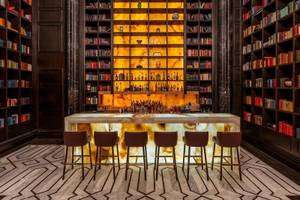 Bar in der Bibliothek des Raffles Doha mit Marmortheke und Bücherregalen.