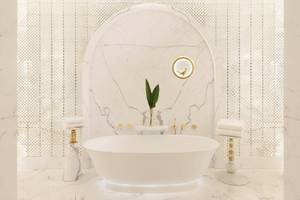 Ein Badezimmer im Raffles Doha Hotel mit einer weißen Badewanne und Marmorboden.