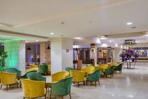 Lobby des Grand Park Lara Hotels mit farbenfrohen Sesseln und einem großen Blumenstrauß.