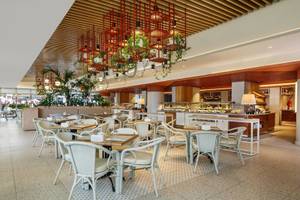 Innenbereich des Grand Park Lara Hotels mit geometrischen Mustern, Tischen und Stühlen, hängenden Pflanzen und einem Büffet.
