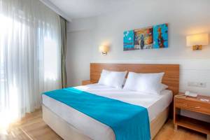 Ein elegantes Hotelzimmer im Grand Park Lara mit einem Bett, blauer Decke, weißen Kissen und Kunst an der Wand.