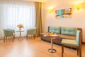 Wohnzimmer des Grand Park Lara Hotels mit Couch, Tisch und Stühlen.