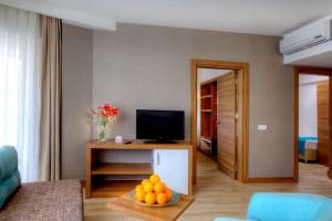Innenansicht eines Hotelzimmers im Grand Park Lara mit Fernseher, Tisch, Obst und Türen.