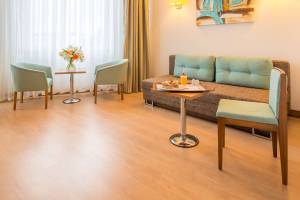 Hotelzimmer mit Sofa, Tisch, Blumen und Kissen.