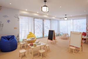 Kinderzimmer im St. Regis Doha mit bunten Wandmalereien, Tischen, Stühlen und einem Sitzsack.