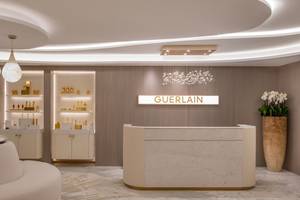 Innenansicht der Guerlain Boutique im St. Regis Doha mit weißem Empfangstresen, Marmorboden und Beleuchtung.