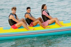 Drei Leute auf einem aufblasbaren Boot im Wasser, alle tragen Schwimmwesten.