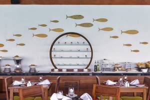 Innenansicht des Restaurants im Summer Island Maldives Hotel mit hölzernen Fischen an der Wand.