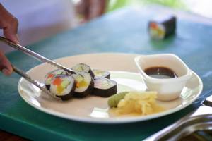 Eine Platte mit verschiedenen Sushi-Rollen und Sojasauce auf einem grünen Tisch.