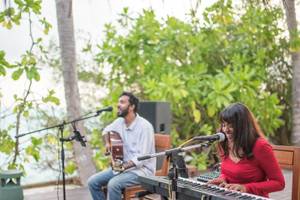 Ein Mann und eine Frau spielen Musik auf der Terrasse des Summer Island Maldives Hotels.