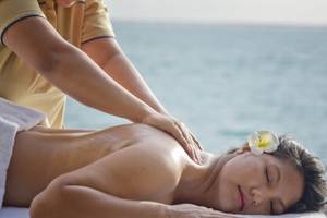 Eine Frau genießt eine Massage am Strand im Sommer Island Maldives Hotel.