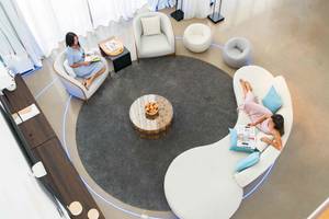 Zwei Frauen lesen in einer Lounge mit weißen Möbeln und einem Tisch mit Früchten im Nikki Beach Resort & Spa Dubai.