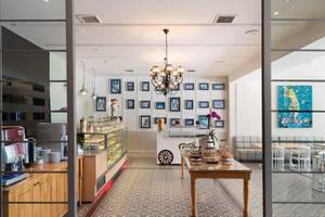 Innenansicht der Rezeption des Turquoise Hotels mit Möbeln, einem Tisch mit Dekoration und Gemälden an der Wand.