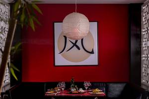 Inneneinrichtung des japanischen Restaurants im Turquoise Hotel mit rotem Hintergrund, hängendem Papierlaternen und Tisch mit Gerichten.