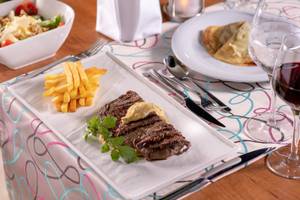 Ein Steakteller mit Pommes Frites und Salat im Turquoise Hotel.