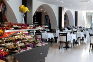 Innenansicht des Restaurants im Turquoise Hotel mit Dessertbuffet und gedeckten Tischen.