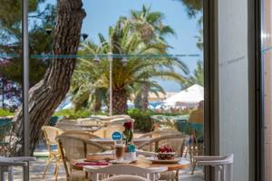 Terrasse im Turquoise Hotel mit Tischen, Stühlen und einer Rose in einem Glas