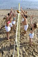 Gruppe junger Leute spielt Volleyball am Strand mit gelbem Netz