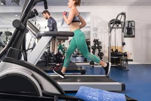 Fitnessstudio im Turquoise Hotel mit einer Frau, die auf einem Laufband läuft.