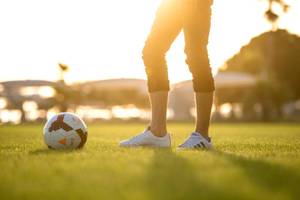 Mann mit Fußball im Stadion, bei Sonnenuntergang