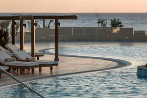 Poolbereich des JAZ Riviera Hotels bei Sonnenuntergang mit Loungestühlen und Meerblick.