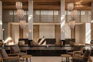 Lobby des JAZ Riviera Hotels mit Empfangstresen, Holzdecken, Marmorboden und modernen Möbeln.