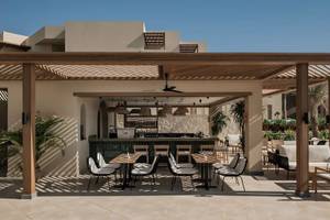 Terrasse im Jaz Riviera Hotel mit Bar, Tischen und Stühlen unter einem Dach.