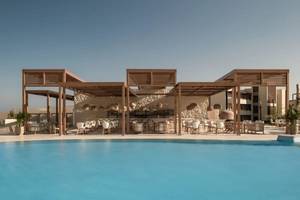 Pool-Lounge-Bereich im JAZ Riviera Hotel mit braunen Überdachungen und weißen Stühlen.