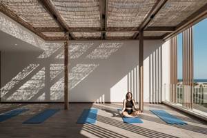 Frau im JAZ Riviera Yoga Studio beim Yoga auf Matte vor Fenstern