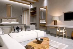 Innenansicht des Schlafzimmers im JAZ Riviera Hotel mit Bett, Sofa, Tisch und Fernseher.