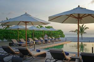 Außenbereich des Brennia Kottefaru Maldives Hotels mit Pool, Liegen und Sonnenschirmen am Meer