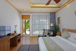 Innenansicht eines Zimmers im Brennia Kottefaru Maldives Hotel mit Fernseher, Bett und Wohnzimmermöbeln.
