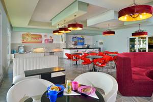 Innenansicht des Restaurants im Paradisus Varadero Resort & Spa mit roten Stühlen und Tischen, weißen Bänken, und bunten Speisen auf dem Tisch.